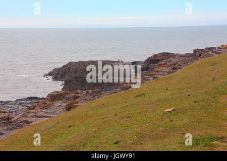 Zwei Leute, Angeln off Rande Klippen warten nur auf eine Kleinigkeit an einem sonnigen Tag Warn. Stockfoto