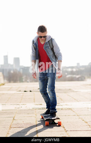 glücklich Jüngling oder Teenager Reiten auf longboard Stockfoto