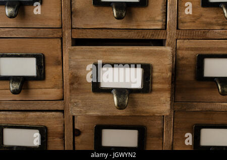 Eine alte Stil Holzgehäuse Bibliothek Kartei Schubladen mit Etikettenhalter und leere Etiketten nach vorne.  Eine Schublade in der Mitte wird geöffnet. Stockfoto