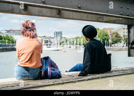 Zwei junge Leute sitzen auf den Docks auf einen Blick auf der Hafenseite in Bristol. Stockfoto