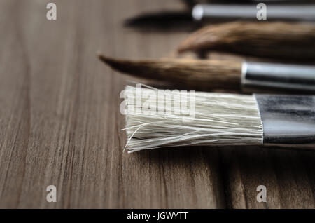 Seitenansicht einer Vielzahl von des Künstlers Pinsel, angelegt in einer Reihe auf einem Holzbrett Tisch hautnah. Stockfoto