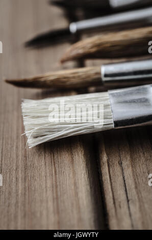 Nahaufnahme von einer Vielzahl von des Künstlers Pinsel, auf einem Holzbrett Tisch. Stockfoto