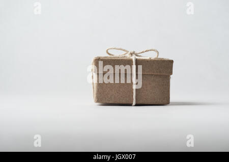 Augen Sie-Ebene Schuss von einem einfach verpackte braunen Karton mit Deckel, an einem Bogen mit einer Schnur gebunden.  Aus weißem Hintergrund. Stockfoto