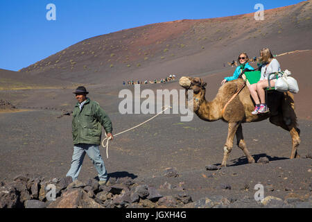 Touristen mit dromedaren, einhoeckriges Kamel (camelus dromedarius) auf den Feuerbergen, Montanas del Fuego, Nationalpark Timanfaya auf Lanzarote, kanari Stockfoto