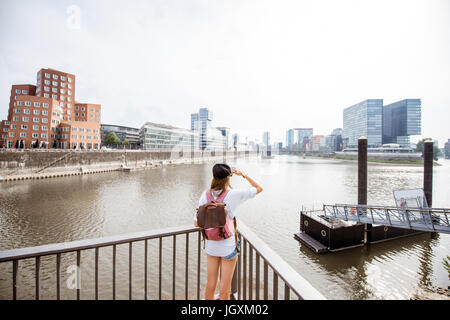 Junge Frau, die große Aussicht auf den Hafen mit modernen Gebäuden in Düsseldorf City, Deutschland Stockfoto