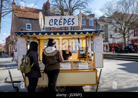 Zwei junge Frauen kaufen Crêpes Crepes in einer Garküche Stree in York, Großbritannien. Stockfoto