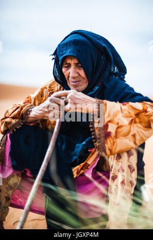Porträt des alten Berber Frau sitzt auf einer Sanddüne in Merzouga, Marokko Stockfoto