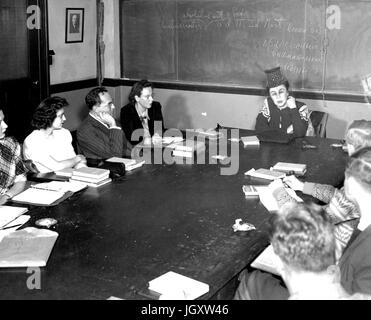 Ein Johns Hopkins University College Abendkurs sitzt an einem Tisch in einem Klassenzimmer der Professor zu betrachten, wie sie, in Baltimore, Maryland, 1940 spricht. Stockfoto