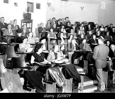 JHU Abend College-Studenten sitzen in einem Hörsaal Notizen wie ihres Professors in den Gängen steht, Vorträge, 1930. Stockfoto