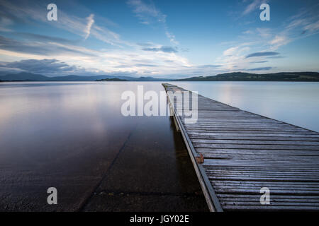 Steg erstreckt sich in einer ruhigen Loch Lomond Stockfoto