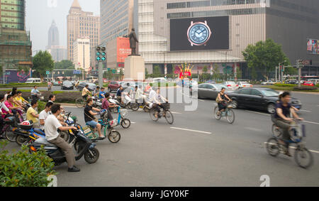 Autos, Fahrräder und Elektroroller verhandeln Xinjiekou in abendlichen Hauptverkehrszeiten. Nanjing, China Stockfoto