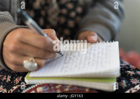 Nahaufnahme von einer Frauenhand schreiben mit einem Stift auf einem Notizblock. Stockfoto