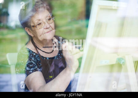 Ältere Erwachsene Frau auf Staffelei malen Stockfoto