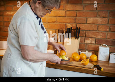 Ältere Erwachsene Frau quetschen Orangen Stockfoto