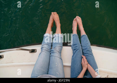 Zwei Frauen, entspannend auf Boot, Anzeigen Füße über Rand des Bootes, barfuß, overhead Stockfoto