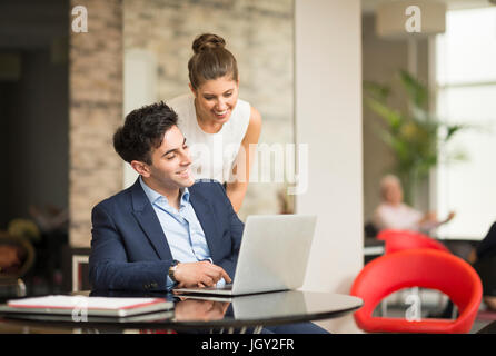 Geschäftsmann und Frau betrachten Laptop im Büro Stockfoto
