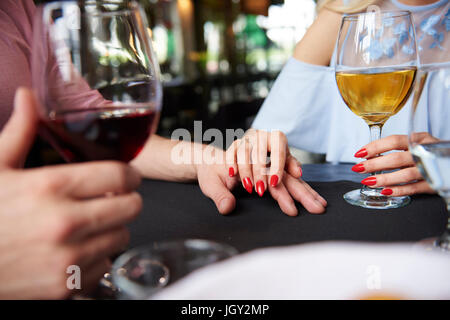 Verkürzte Sicht von Frauenhand auf Freundes Hand am Tisch im restaurant Stockfoto