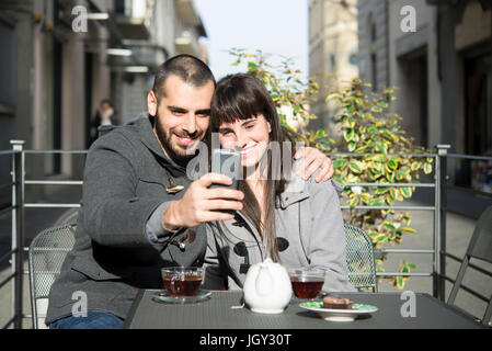 Junges Paar sitzt außerhalb Café, wobei Selfie, mit smartphone Stockfoto