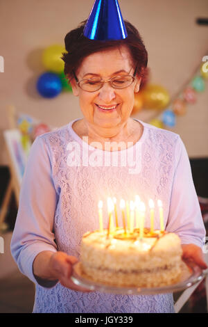 Ältere Frau mit Geburtstagstorte auf party Stockfoto