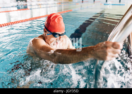 Senior woman über Leiter im Schwimmbad Stockfoto