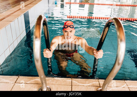 Senior woman über Leiter im Schwimmbad Stockfoto