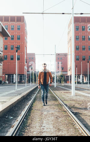 Coole junge bärtigen Mann zu Fuß entlang der Straßenbahn-Linien Stockfoto