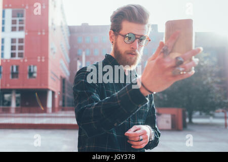 Coole junge männliche Hipster unter Smartphone Selfie in Stadt Stockfoto