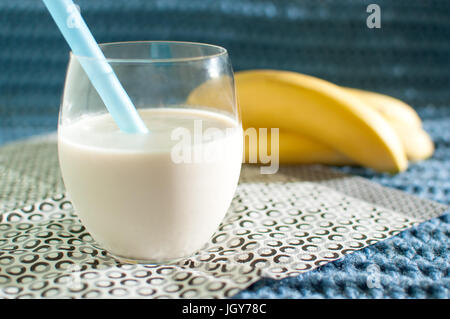 Gesunde Ernährung. Bananen-Smoothies. Milchshake und reife Bananen auf blauem Stoff gestrickt Hintergrund Stockfoto