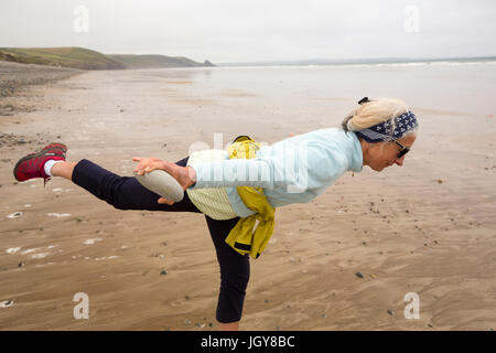 Ein Frauen praktizieren Pilates auf Newgale Sands in Pembrokeshire, Wales, Großbritannien. Stockfoto