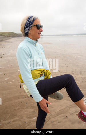 Ein Frauen praktizieren Pilates auf Newgale Sands in Pembrokeshire, Wales, Großbritannien. Stockfoto