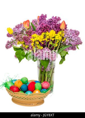 Bunte Ostereier und eine transparente Vase mit den Blumen: violette und weiße Syringa Vulgaris, rote Tulpen Stockfoto