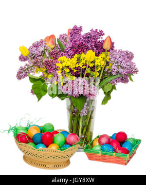 Bunte Ostereier und eine transparente Vase mit den Blumen: violette und weiße Syringa Vulgaris, rote Tulpen Stockfoto