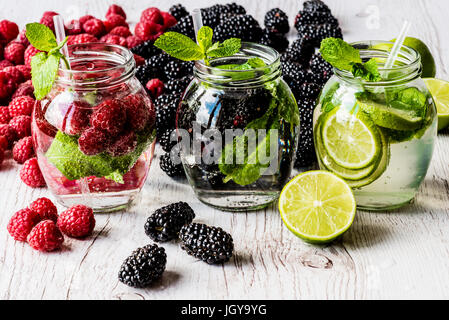 Drei Arten von Detox Wasser mit Brombeere, Erdbeere, lime mit Zutaten auf weißem Hintergrund aus Holz. Stockfoto