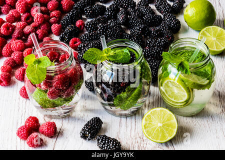 Drei Arten von Detox Wasser mit Brombeere, Erdbeere, lime mit Zutaten auf weißem Hintergrund aus Holz. Stockfoto