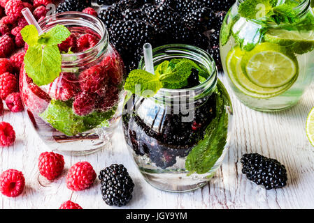 Drei Arten von Detox Wasser mit Brombeere, Erdbeere, lime mit Zutaten auf weißem Hintergrund aus Holz. Stockfoto