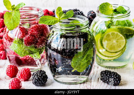 Drei Arten von Detox Wasser mit Brombeere, Erdbeere, lime mit Zutaten auf weißem Hintergrund aus Holz. Stockfoto