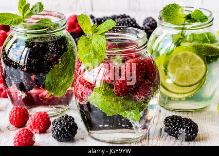 Drei Arten von Detox Wasser mit Brombeere, Erdbeere, lime mit Zutaten auf weißem Hintergrund aus Holz. Stockfoto