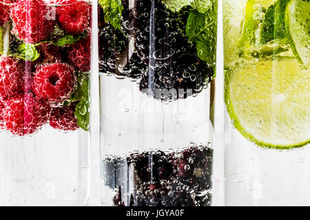 Drei Arten von Detox Wasser mit Brombeere, Erdbeere, lime mit Zutaten auf weißem Hintergrund aus Holz. Stockfoto