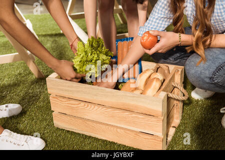 Aufnahme von jungen Frauen, die Abhaltung von Zutaten für Grill vom Picknick-Korb beschnitten Stockfoto