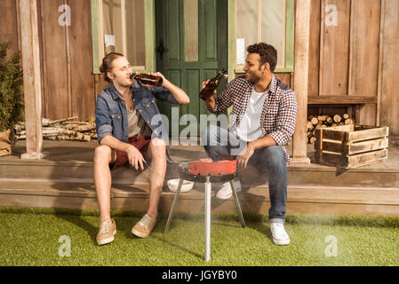 Zwei junge Männer Bier trinken und Zubereitung von Fleisch am Grill im freien Stockfoto