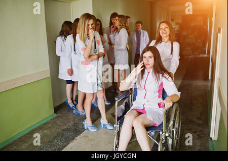 Verrückte junge Ärzte Spaß durch posiert auf einem Rollstuhl auf dem Flur des Krankenhauses. Stockfoto