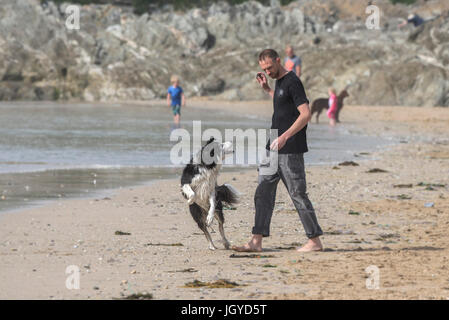 Ein Mann wirft einen Stein für seinen Hund an einem Strand. Stockfoto