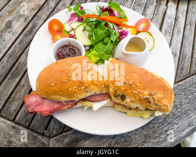 Mittagsimbiss auf einem Tisch für draußen Speck und Brie Rollen mit Gurken Salat und dressing Stockfoto
