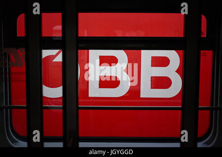 OBB, das Logo der österreichischen Bundesbahn, auf der Seite einen Zug von einem anderen Zug gesehen. Stockfoto
