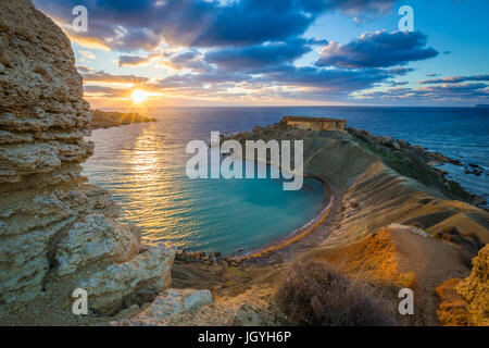 Mgarr, Malta - Panorama von Gnejna Bay, dem schönsten Strand in Malta bei Sonnenuntergang mit schönen bunten Himmel und goldenen Felsen Ta Lippija entnommen Stockfoto