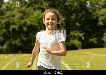 Mädchen am Schulsporttag laufen. Junges Kind sprinten hart und glücklich während der traditionellen Schule Sommerevent Stockfoto