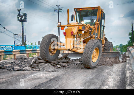 gelbe Grader im Sommer auf der asphaltierten Straße fahren Stockfoto