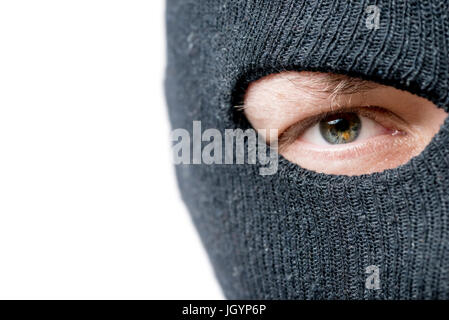 Nahaufnahme der Augen an das Verbrechen, dessen Gesicht durch eine schwarze Maske und den Raum auf der linken Seite abgedeckt ist Stockfoto