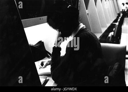 Johns Hopkins University Student sitzt an einer Studie Station lesen mit ihrem Kopf in die Hand, in der Universität Milton S Eisenhower Library in Baltimore, Maryland, 1965. Stockfoto