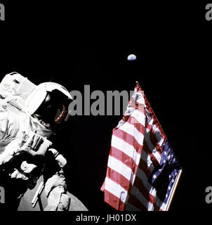 Schmitt mit Flagge und Erde oben. Geologe-Astronaut Harrison Schmitt, Pilot der Mondlandefähre von Apollo 17, ist neben der amerikanischen Flagge während Extravehicular Activity (EVA) von der Mission der NASA letzten Mondlandung der Apollo-Serie fotografiert. Das Foto wurde am Taurus-Littrow-Landeplatz. Der höchste Teil der Flagge scheint in Richtung unseres Planetenerde im fernen Hintergrund zeigen... Fotograf: NASA Eugene Cernan Stockfoto